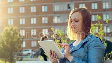 坐在城市长凳上用平板电脑的女人